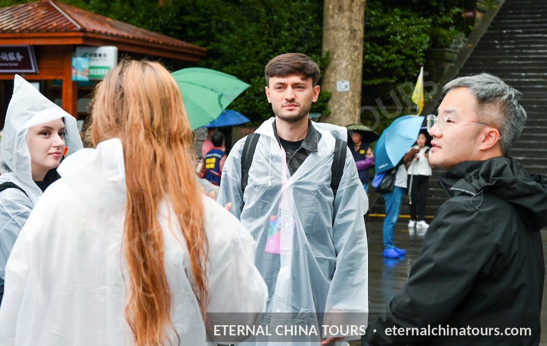 Travelers in rain ponchos listening to their guide