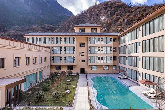 Grand Rezen Jiuzhaigou Resort exterior with pool and mountains